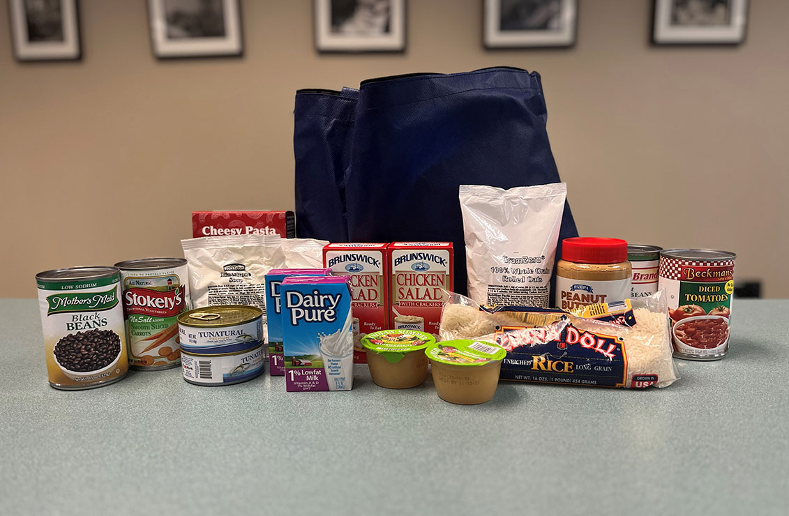 assortment of health, non-perishable foods, displayed on a table in front of a reusable grocery bag